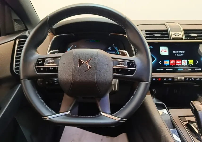 Vue frontale du volant cuir noir DS d’un DS7 Crossback E-TENSE 225 BUSINESS avec tableau de bord numérique et écran tactile.