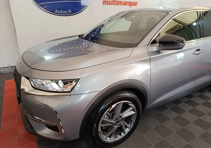 Vue 3/4 avant droit du DS7 Crossback E-TENSE 225 Business gris foncé, avec jantes alliage et phares LED distinctifs.