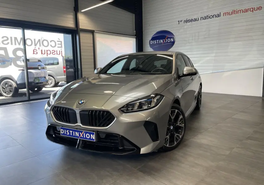 BMW Série 1 120d M Sport gris en 3/4 avant dans un showroom avec jantes 18 pouces bicolores et calandre noire.