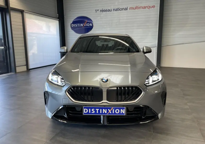 Vue frontale d'une BMW Série 1 120d M Sport gris avec calandre noire et projecteurs LED allumés en showroom.