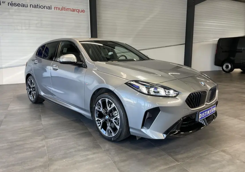 BMW Série 1 120d M Sport gris vue 3/4 avant droit, avec jantes bicolores et calandre noire sportive.