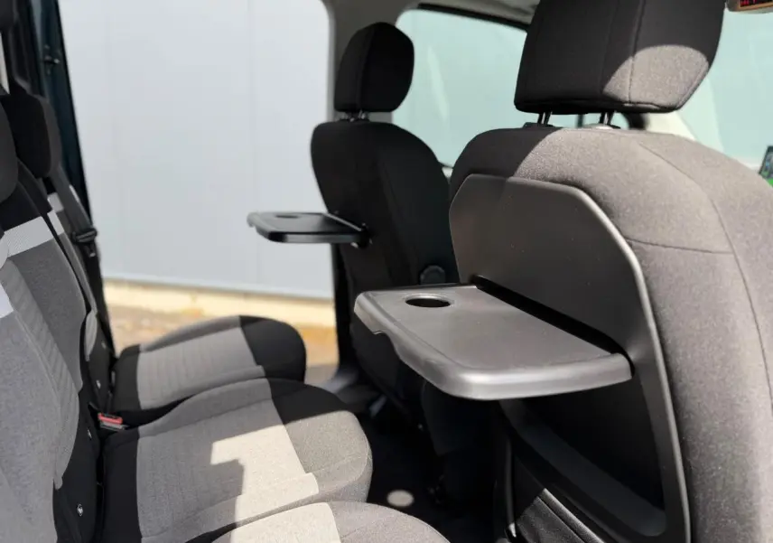 Vue intérieure côté droit des sièges arrière gris avec tablettes rabattables sur les dossiers avant du Citroën Berlingo Multispace.