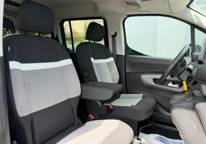Vue intérieure côté conducteur du Citroën Berlingo Multispace 2026, sièges tissu gris et noir avec accoudoir.
