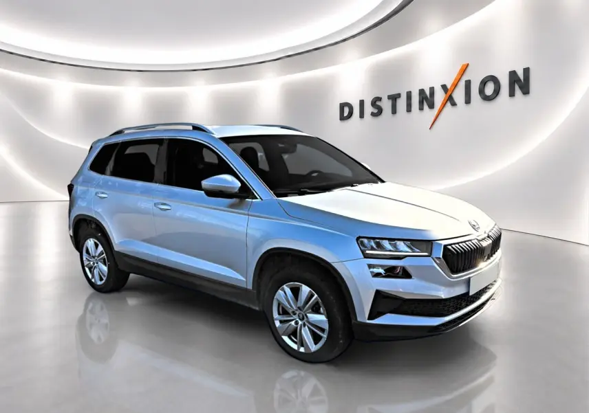 Vue 3/4 avant droite d'un Skoda Karoq gris métallisé dans un showroom lumineux avec jantes alu.