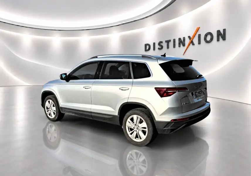 Vue 3/4 arrière droite d'un Skoda Karoq gris métallisé dans un showroom lumineux avec jantes alu.