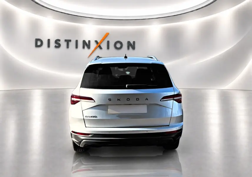Vue arrière d'un Skoda Karoq gris 2025 dans un showroom avec logo Distinxion en arrière-plan.