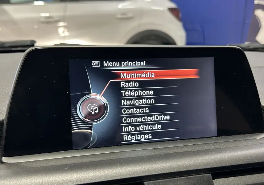Écran central de la BMW Série 1 116d 2015 affichant le menu principal multimédia en intérieur.