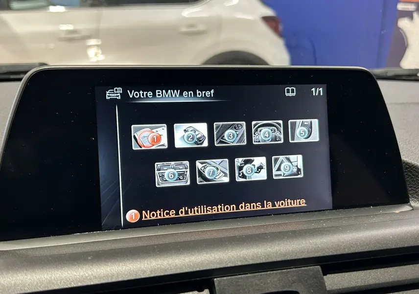 Écran central affichant le menu d’aide de la BMW Série 1 blanche, vue intérieure du tableau de bord.