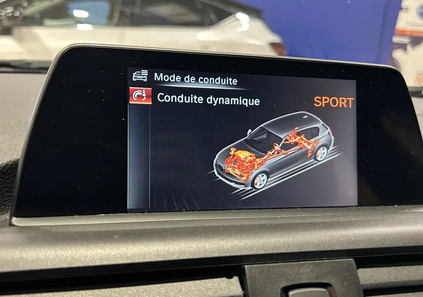 Écran central de BMW Série 1 116d blanc montrant le mode de conduite dynamique SPORT avec schéma technique du véhicule.