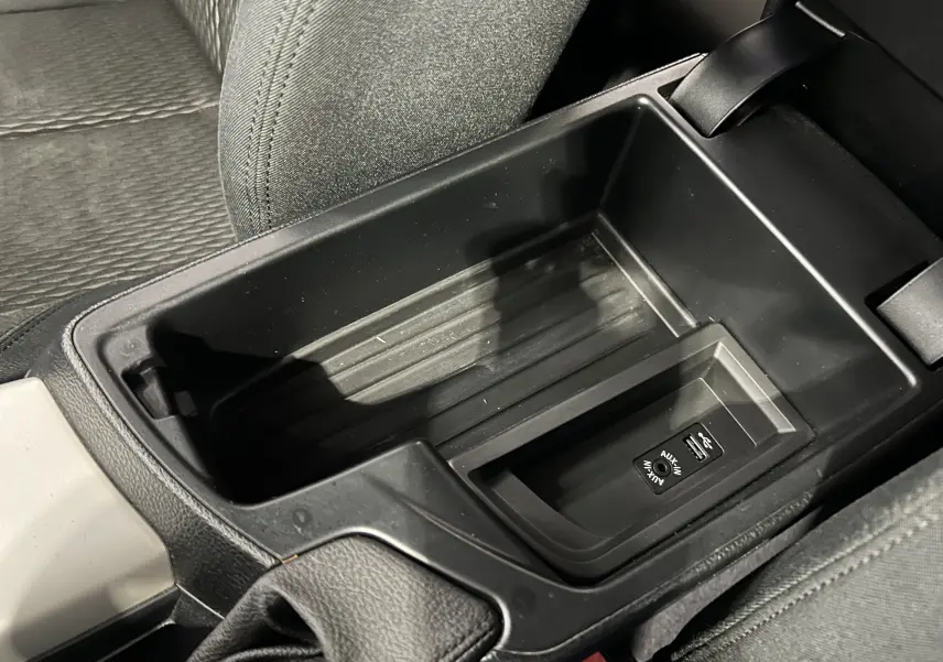 Gros plan sur la console centrale noire de la BMW Série 1 116d, montrant un rangement avec prise USB et entrée AUX.