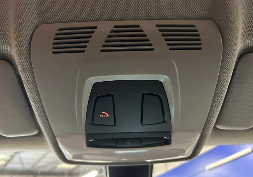 Vue en gros plan du plafonnier intérieur gris clair avec bouton SOS rouge de la BMW Série 1 116d Business 2015 blanche.