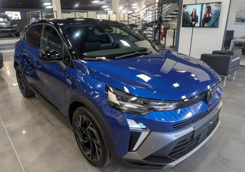 Vue 3/4 avant droite du Renault Captur E-TECH Full Hybrid 2025 en bleu Iron avec toit noir dans un showroom.