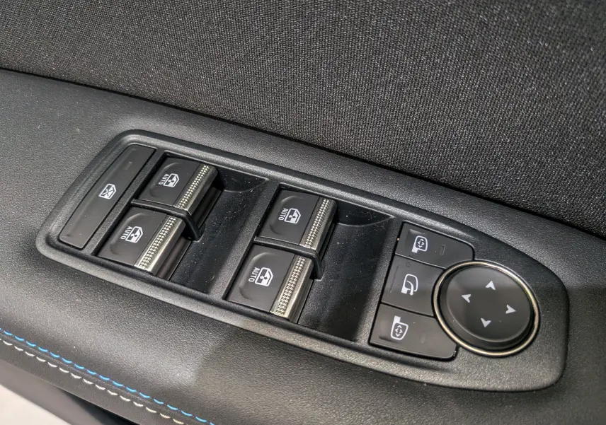 Panneau de commandes des vitres et rétroviseurs côté gauche avec surpiqûres bleues dans un Renault Captur E-Tech hybride 2025.