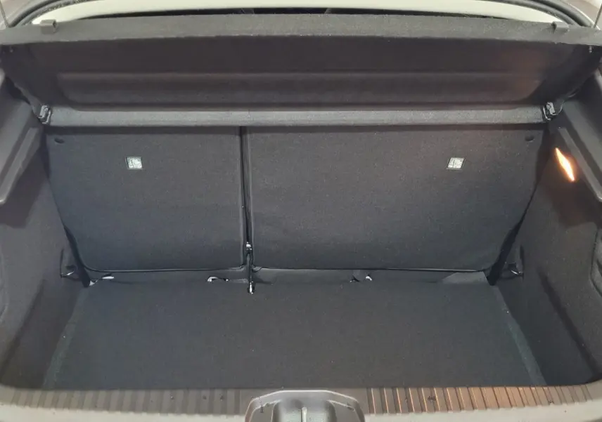 Coffre ouvert vu de l'arrière d'une Renault Clio gris foncé, montrant l'espace de chargement et la banquette arrière rabattue.