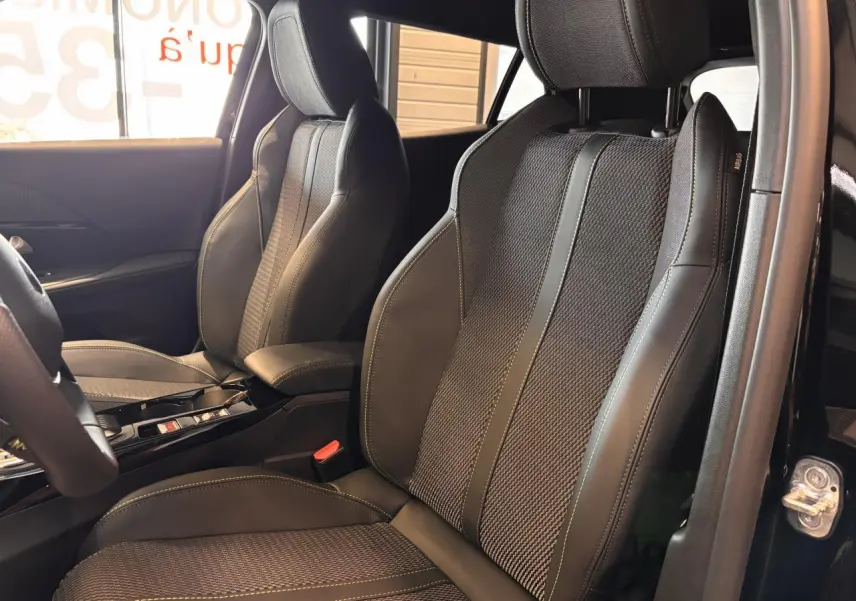 Gros plan sur les sièges avant en tissu et cuir noir du Peugeot 2008 GT 2025, avec surpiqûres contrastantes visibles.