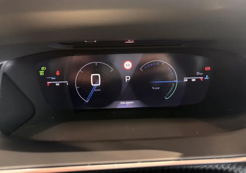 Tableau de bord numérique du Peugeot 2008 blanc 2025, affichant la vitesse à 0 km/h et indicateurs hybrides.