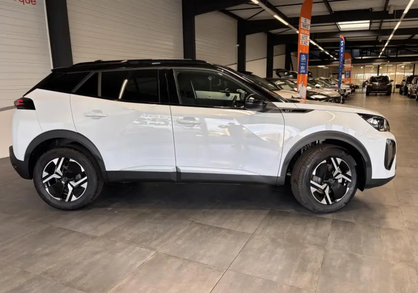 Profil droit du Peugeot 2008 blanc hybride 2025 en intérieur, avec toit noir et jantes distinctives bicolores.