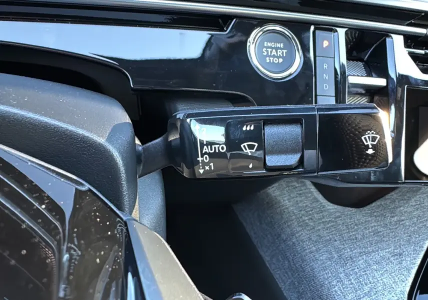 Gros plan sur la commande d’essuie-glace et le bouton start/stop dans l’habitacle du Peugeot 3008 Hybrid blanc toit noir.