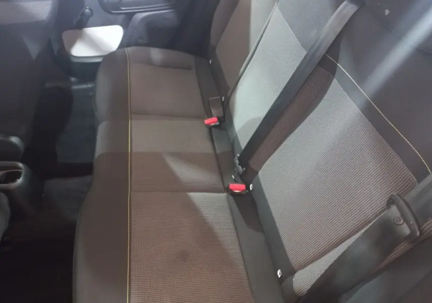 Vue intérieure de la banquette arrière grise et noire de la Citroën C3 2024 avec ceintures et boucle rouge visibles.
