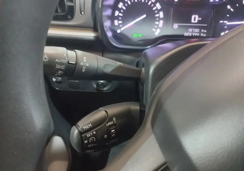 Gros plan sur le volant et le tableau de bord de la Citroën C3 2024, montrant les commandes de régulateur et les compteurs lumineux.