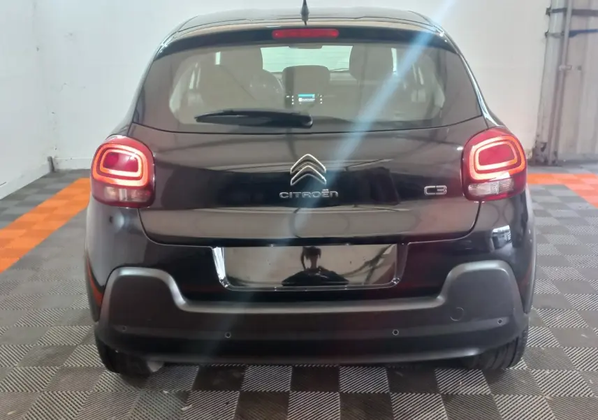 Vue arrière d'une Citroën C3 noire 2024 avec feux arrière LED allumés dans un garage.