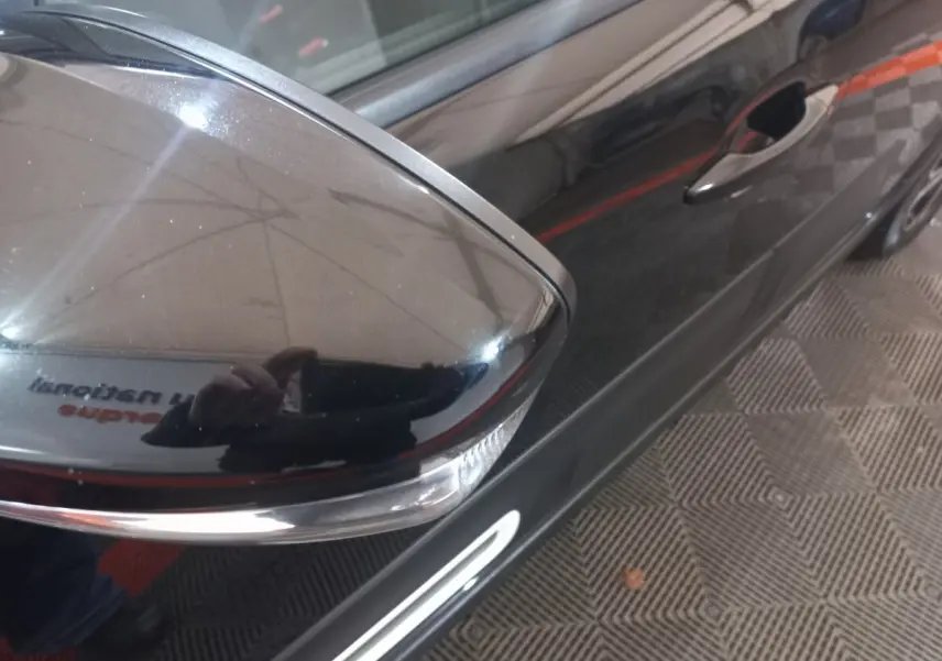 Gros plan sur le rétroviseur droit noir brillant de la Citroën C3 2024, avec poignée de porte et partie latérale visibles.