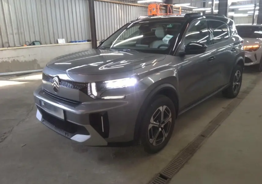 Citroën C3 Aircross électrique gris Mercury avec toit noir, vue 3/4 avant droit en intérieur d'atelier.