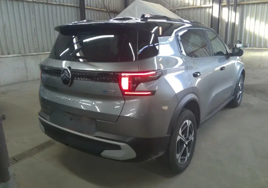 Vue 3/4 arrière droite d'une Citroën C3 Aircross électrique gris Mercury avec toit noir et feux arrière LED allumés.