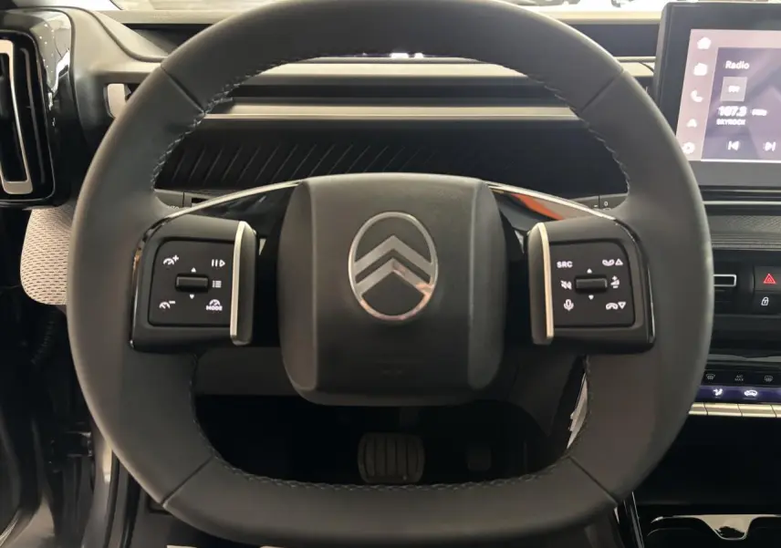 Vue rapprochée du volant multifonctions noir du Citroën C3 Aircross 2026 avec commandes tactiles et logo central chromé.