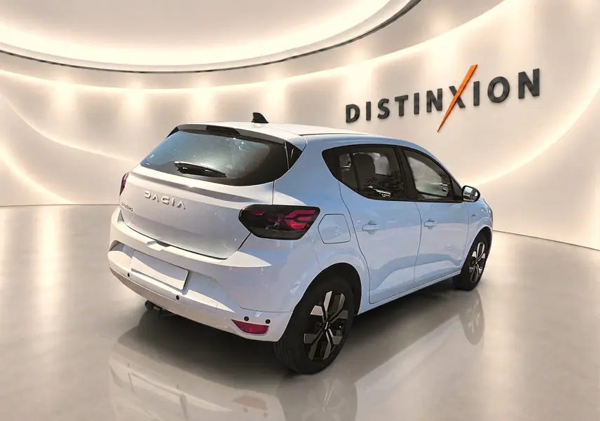 Vue 3/4 arrière droite d'une Dacia Sandero blanche 2025 avec jantes alu et feux arrière LED noirs.