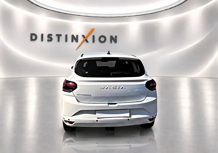 Vue arrière d'une Dacia Sandero blanche 2025 dans un showroom avec logo Distinxion en arrière-plan.