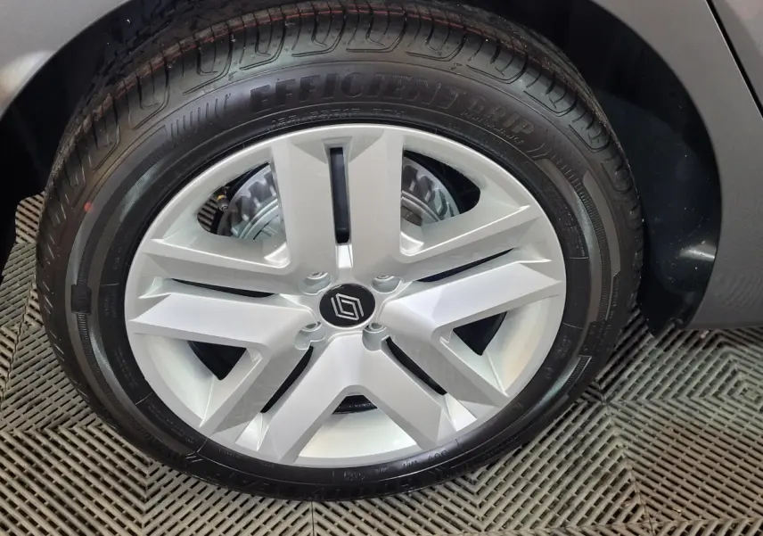 Gros plan sur la roue arrière droite d'une Renault Clio gris foncé, mettant en valeur le pneu et l'aile du véhicule.