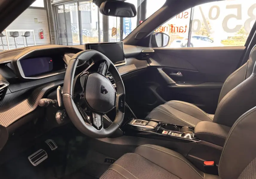 Intérieur du Peugeot 2008 gris 2025, vue côté conducteur, volant multifonction et écran central moderne.