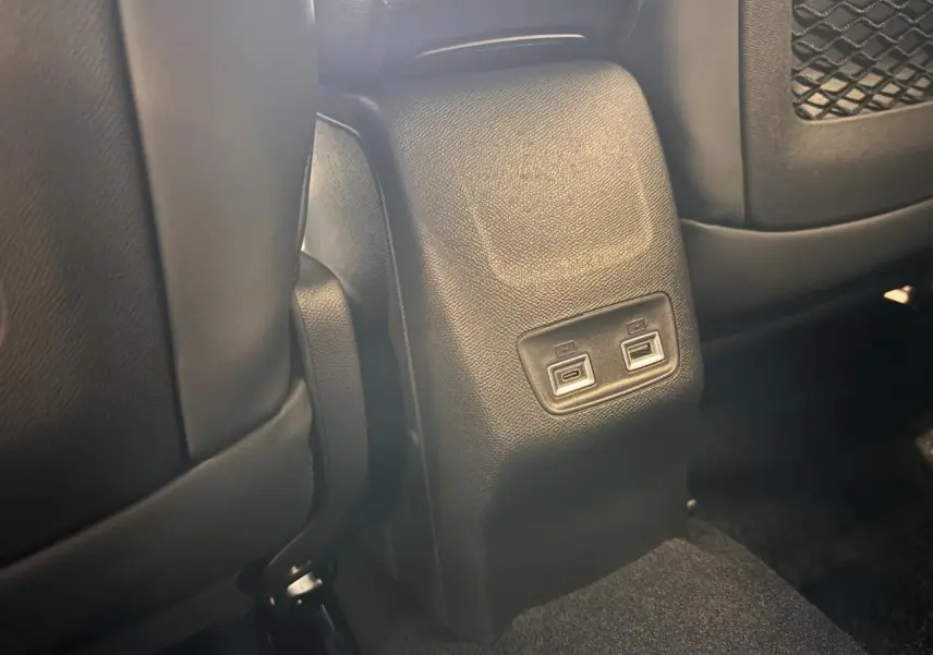 Prise USB arrière double sur console centrale noire, entre les sièges avant du Peugeot 2008 gris hybride 2025.