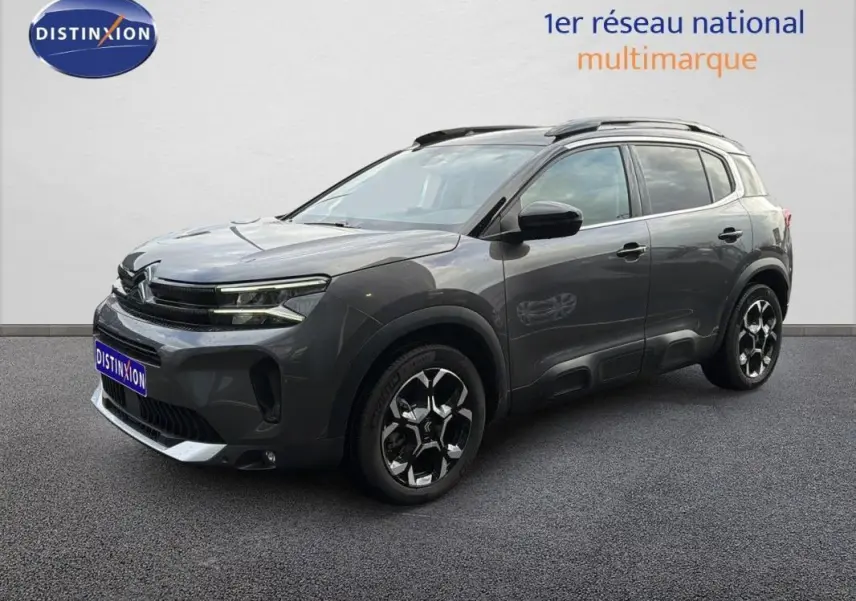 Vue 3/4 avant droite du Citroën C5 Aircross platine 2025 avec barres de toit et jantes aluminium distinctives.