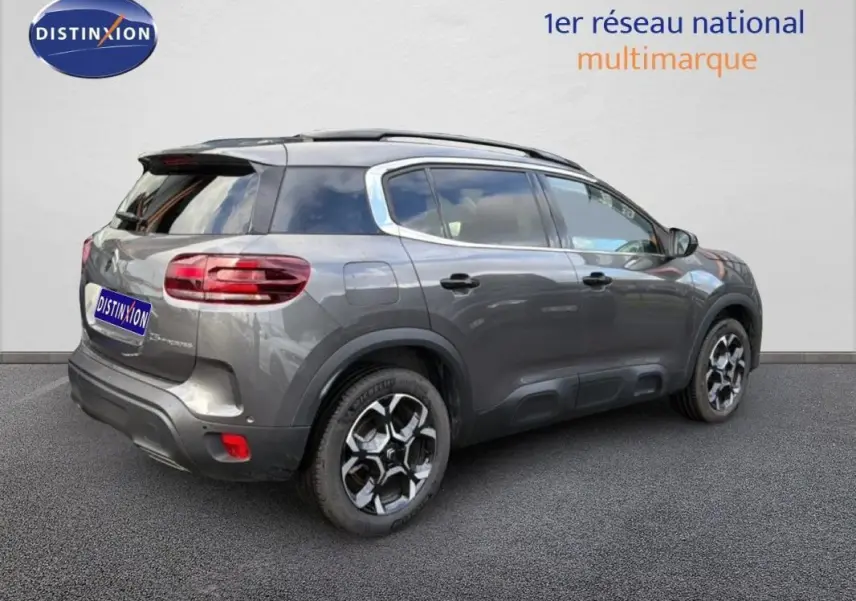Vue 3/4 arrière droite d'un Citroën C5 Aircross platine avec barres de toit et jantes aluminium distinctives.