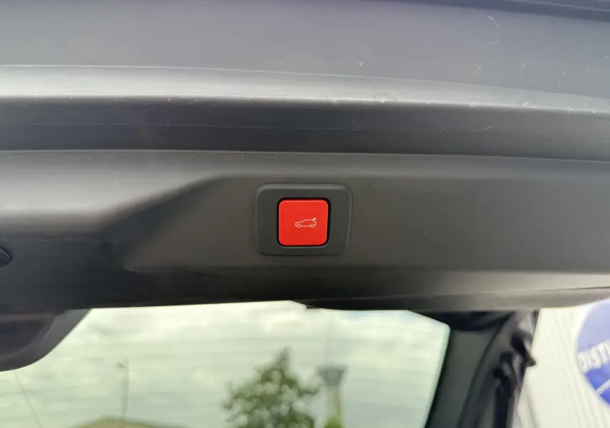 Bouton rouge de fermeture électrique du hayon visible depuis l'intérieur du coffre du Peugeot 3008 blanc toit noir.