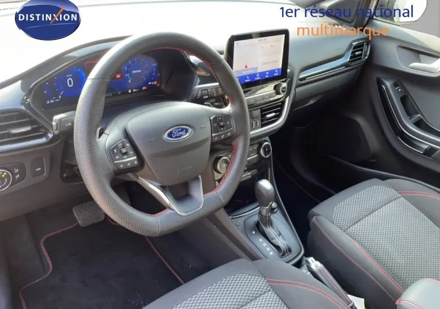 Vue intérieure avant droite du Ford Puma 2023, volant cuir noir avec surpiqûres rouges et écran tactile central.