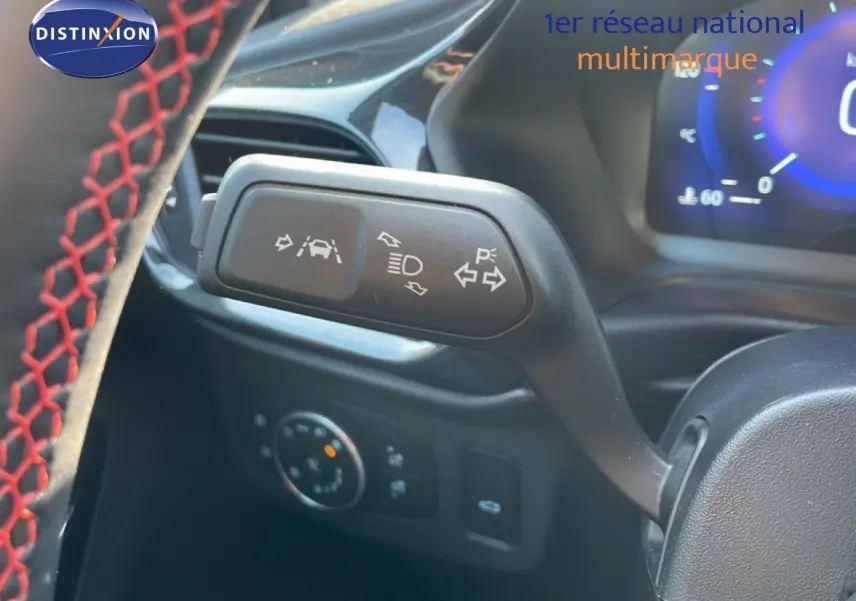 Gros plan sur la manette de clignotants et aides à la conduite du Ford Puma noir Agate, volant avec surpiqûres rouges visible.