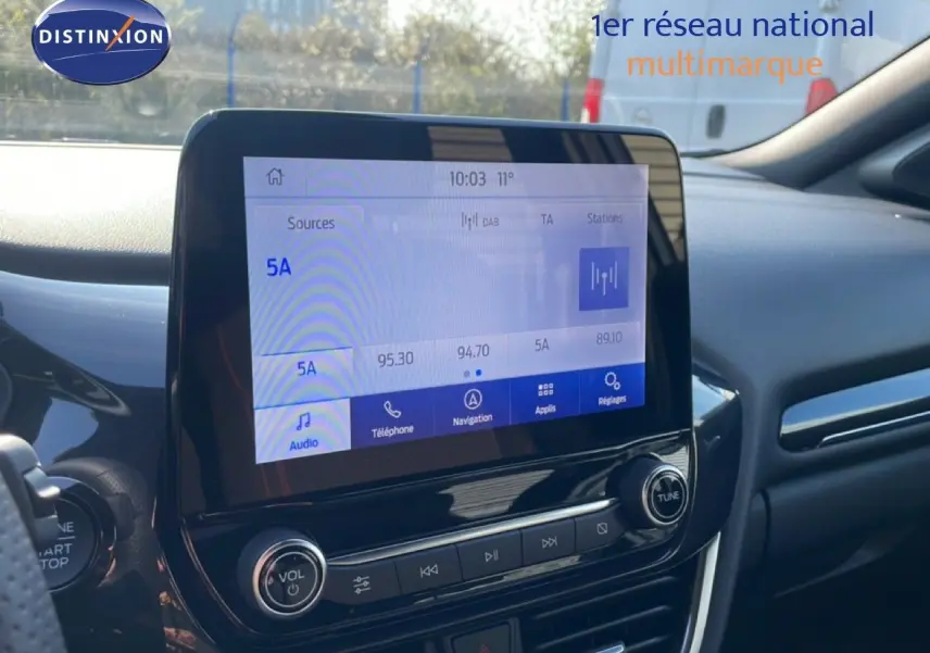 Vue intérieure du tableau de bord du Ford Puma 2023 noir agate métal, avec écran tactile central et commandes audio visibles.