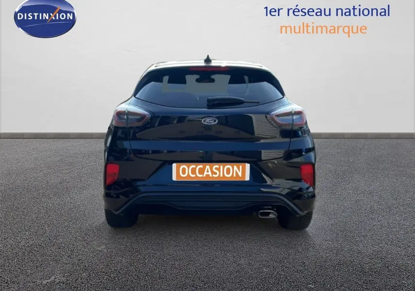 Vue arrière d'une Ford Puma noire Agate Métal 2023 avec feux LED et sortie d'échappement visible sur sol bitumé.
