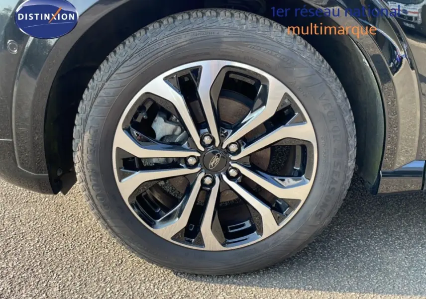 Gros plan sur la roue avant gauche du Ford Puma noir agate métal avec jante alliage bicolore et pneu Goodyear.