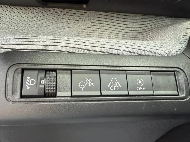 Vue rapprochée des commandes noires du tableau de bord de la Citroën C3 2025, avec tissu gris en arrière-plan.