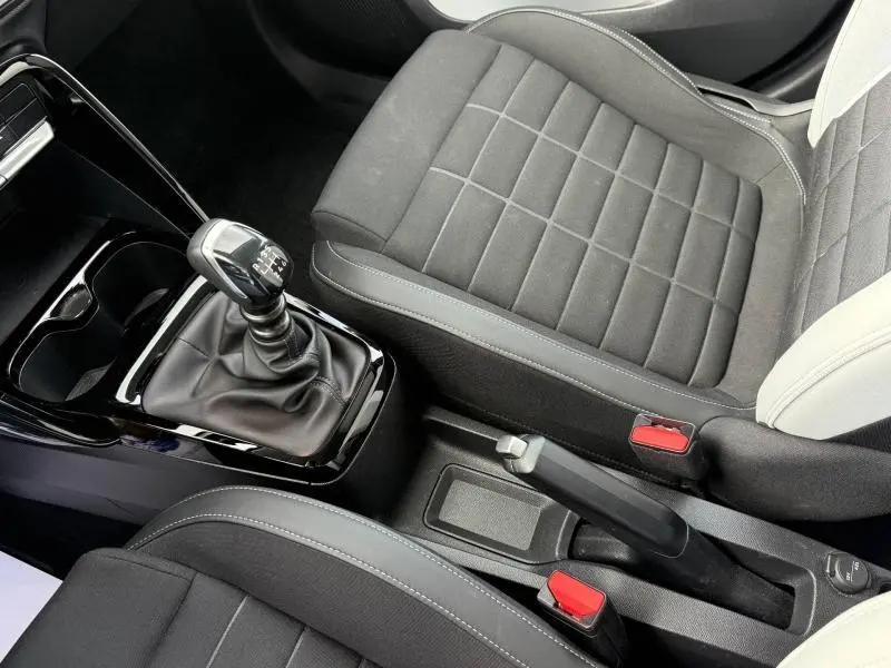 Vue rapprochée de l'intérieur de la Citroën C3 2025, montrant la boîte manuelle et les sièges en tissu noir avec surpiqûres grises.