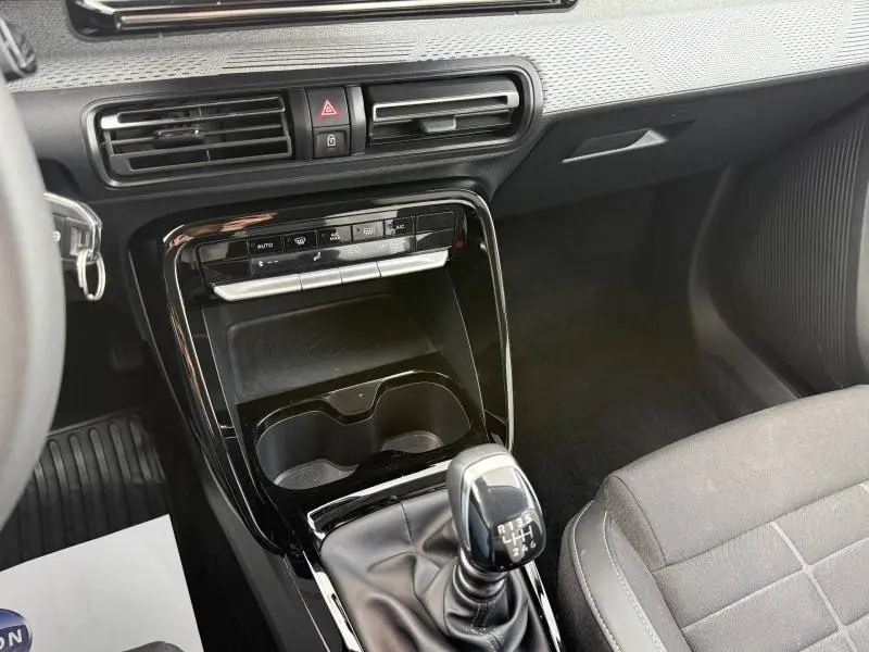 Vue intérieure centrée sur la console centrale noire brillante et le levier de vitesse manuel de la Citroën C3 2025.