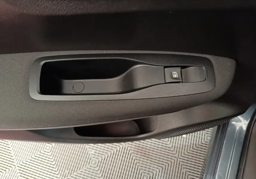 Détail de la commande de lève-vitre côté conducteur sur la porte intérieure du Renault Kadjar gris foncé.