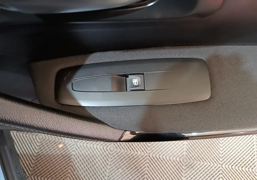 Gros plan sur le bouton de commande de la vitre électrique côté conducteur du Renault Kadjar gris foncé.