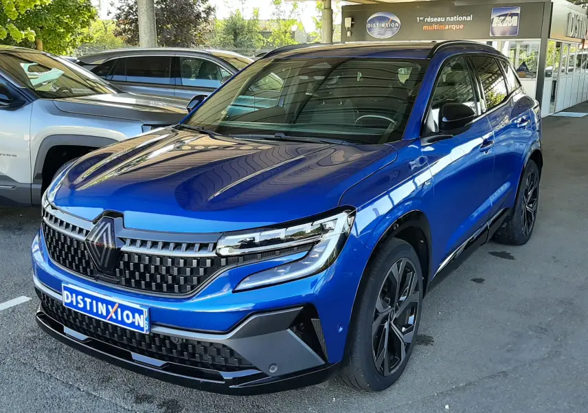 Renault Austral E-Tech 200 Techno Esprit Alpine bleu Iron, vue 3/4 avant sous abri avec calandre distinctive noire.