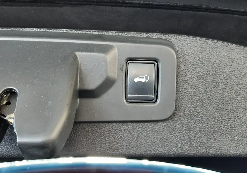 Bouton d'ouverture électrique du hayon sur le bord intérieur du coffre d'un Renault Austral Bleu Iron 2023.