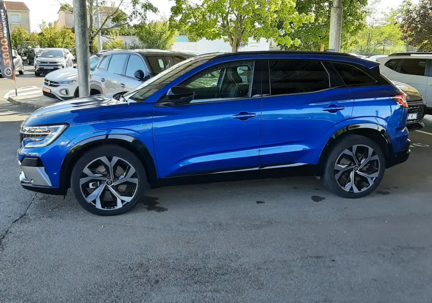 Profil côté gauche du Renault Austral E-Tech 200 Technno Esprit Alpine bleu Iron 2023, sous abri avec jantes distinctives.